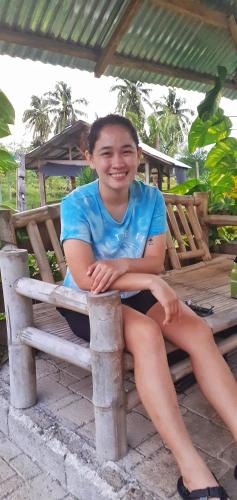 a young girl sitting on a bench at House of TamSe Laagans ' Inn in Badian