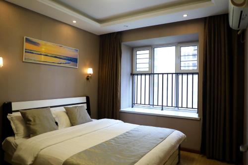 a bedroom with a large bed and two windows at Sea View Apartment Qingdao North Railway Station Branch in Xiazangtuan