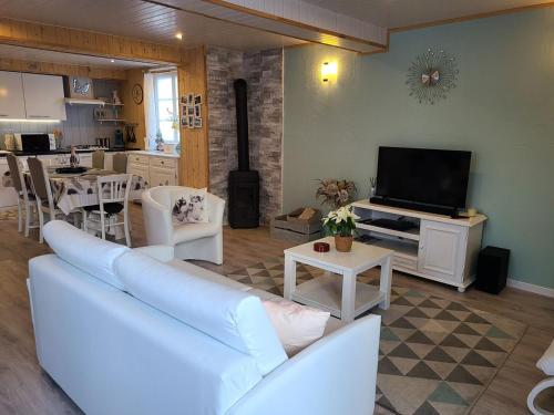 un salon avec un canapé blanc et une télévision dans l'établissement Gîte cosy à Taintrux : nature, rando, proche Gérardmer, Saint-Dié, Alsace, tout confort inclus - FR-1-589-457, à Taintrux