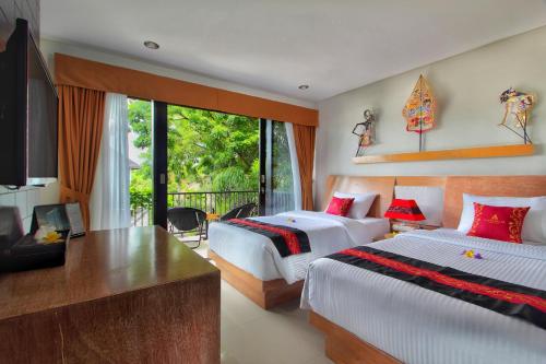 a bedroom with two beds and a desk and a television at Agata Villas Seminyak in Seminyak