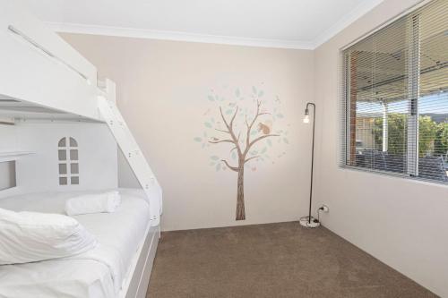 a white bedroom with a tree mural on the wall at Sandylands Busselton with WiFi in Vasse