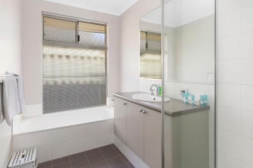 a white bathroom with a tub and a sink at Sandylands Busselton with WiFi in Vasse