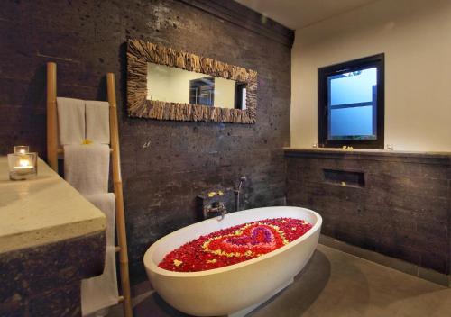 a bathroom with a large bath tub covered in red flowers at Agata Villas Seminyak in Seminyak