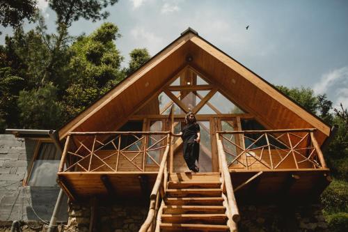 a man standing on the stairs of a house at Stargazing Cottages Jibhi in Jibhi