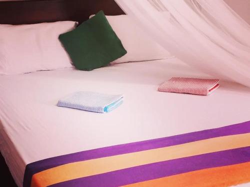 a bed with two colorful pillows on top of it at Talalla Wonder View in Talalla South