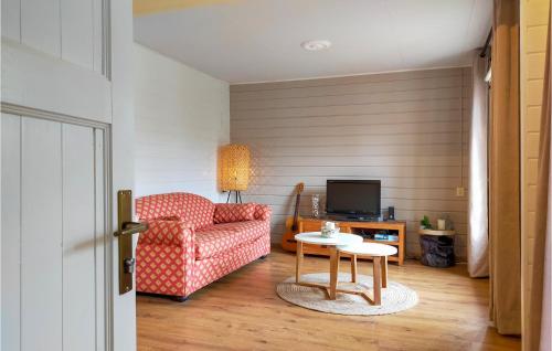 a living room with a red chair and a table at Nice Home In Heinkenszand With Sauna in Heinkensand
