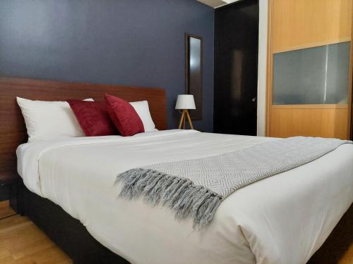 a bedroom with a large white bed with red pillows at Punto Alameda - Reforma in Mexico City