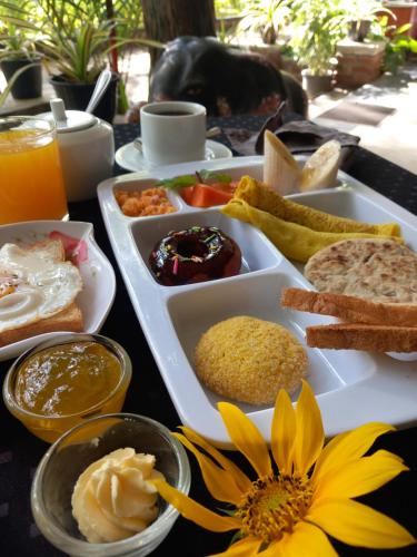 a table topped with a tray of food with a flower at The Nature Park Villa in Sigiriya