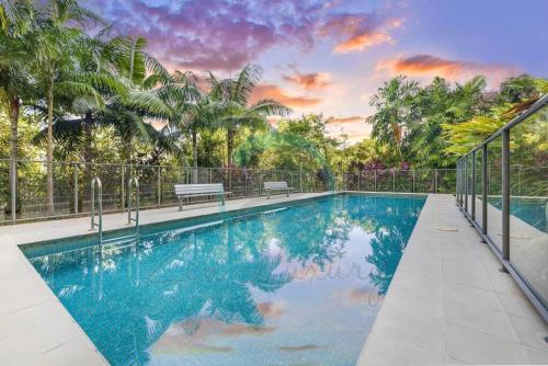 a swimming pool with two benches and palm trees at Zen Ocean Charm 3BR Luxury W/front Apt Pool + BBQ in Darwin