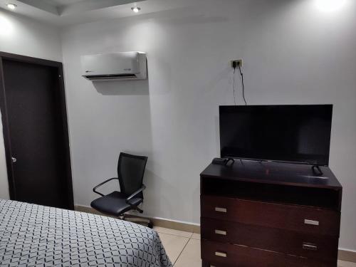 een slaapkamer met een bed en een dressoir met een televisie bij Hotel Don Quijote in Mexicali