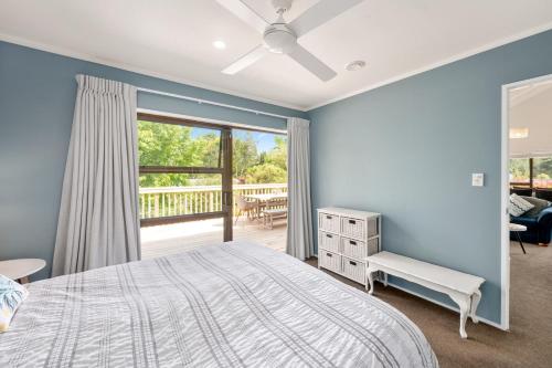 una camera blu con un letto e un balcone di Waitahanui Lake House - Lake Taupo Holiday Home a Waitahanui