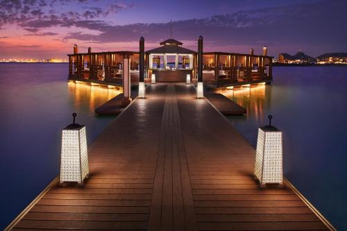 a dock with lights on the water at night at Banana Island Resort Doha by Anantara in Doha