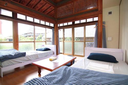 Kinkoにある錦江町ゲストハウス よろっでのベッド2台、テーブル、窓が備わる客室です。