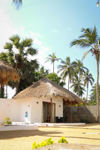 a hut on the beach with palm trees at The Blue Lagoon Resort Kalpitiya in Kalpitiya