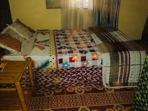 a bed with a quilt on it in a room at Under Volcanoes View Guest House in Nyarugina