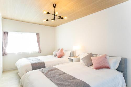 桑名市にあるNagashima Riverside Resortの白い壁の客室で、ベッド2台、窓が備わります。