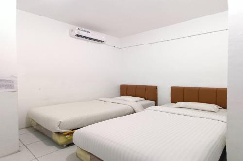 two beds in a room with white walls at OYO 92207 Hotel Koperasi in Banda Aceh