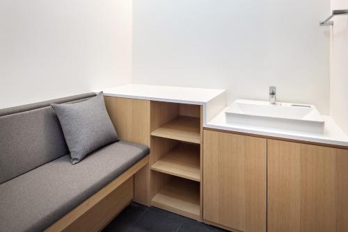 La salle de bains est pourvue d'un lavabo et d'un canapé à côté d'un lavabo. dans l'établissement Shilla Stay Yeosu, à Yeosu