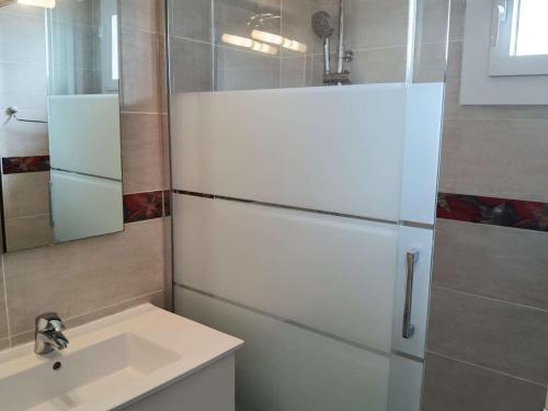 La salle de bains est pourvue d'un évier et d'un réfrigérateur blanc. dans l'établissement Appartement cosy 2 pièces cabine, terrasse, WIFI, parking privé, proche plage à Marseillan - FR-1-326-516, à Marseillan