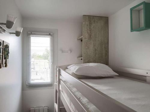 une chambre blanche avec un lit et une fenêtre dans l'établissement Appartement cosy 2 pièces cabine, terrasse, WIFI, parking privé, proche plage à Marseillan - FR-1-326-516, à Marseillan