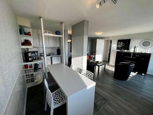 Il dispose d'une cuisine et d'un salon avec un comptoir et des chaises blancs. dans l'établissement Quiberon - Appartement 2 pièces, terrasse, animaux permis, parking - FR-1-478-54, à Quiberon