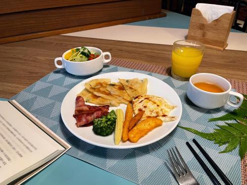 um prato de comida com carne e batatas e um copo de sumo de laranja em Green World Flora Annex em Taipei