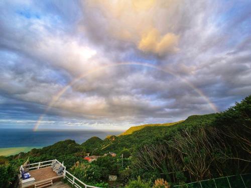 a rainbow in the sky over the ocean at A Promised Land BnB in Jiufen