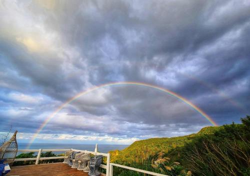 a rainbow in the sky over a deck with chairs at A Promised Land BnB in Jiufen