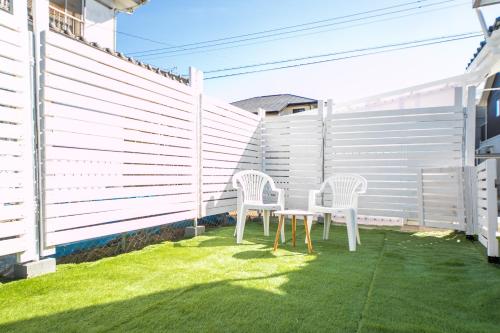 two white chairs and a table in a yard at Nagashima Riverside Resort 1 in Kuwana