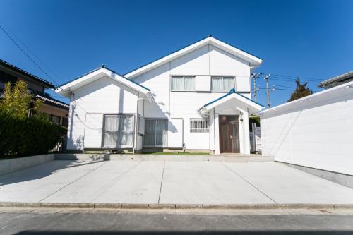 a white house with a driveway at Nagashima Riverside Resort 1 in Kuwana