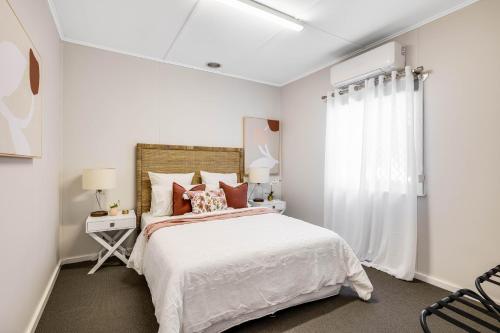 a white bedroom with a bed and a window at Cute & Cheerful! Close to CBD & Gorgeous Parkland! in Toowoomba