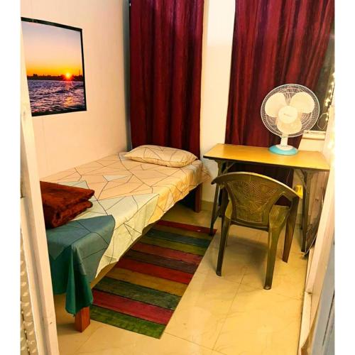 a small bedroom with a bed and a desk with a fan at Cupidtrails Backpacker's Penthouse in Guwahati