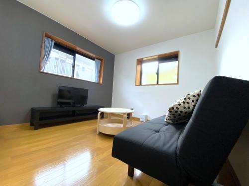 a living room with a black couch and a table at ブルーセレスト数山 in Numazu