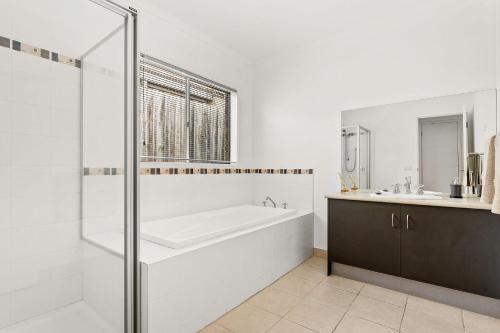 a white bathroom with a tub and a sink at Shallow Water Retreat in Cowes
