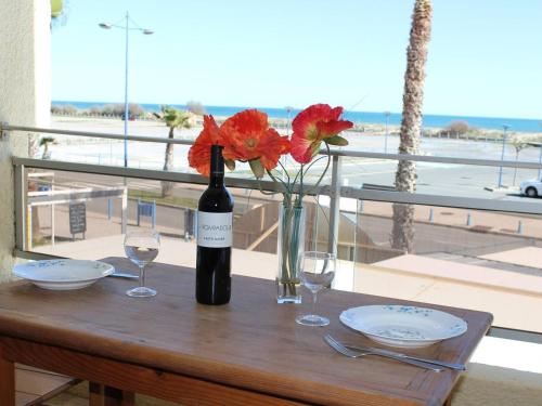- une bouteille de vin et des verres sur une table avec des fleurs dans l'établissement Studio en Front de Mer à Saint-Pierre-la-Mer avec Loggia - 100m de la Plage, 200m du Centre - FR-1-229D-61, à Fleury