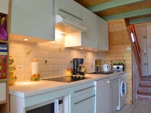 une cuisine avec des armoires blanches et un comptoir dans l'établissement Maison familiale climatisée, 6 couchages, proche plage et centre, terrasse, parking privé - FR-1-229D-79, à Fleury