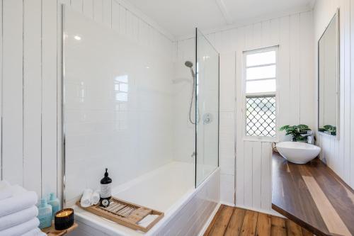 Baño blanco con bañera y lavamanos en Cheerful, Cosy Cottage - Near Rose Garden!, en Toowoomba