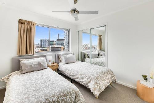 een slaapkamer met 2 bedden en een groot raam bij Spacious Inner city Apartment in Brisbane