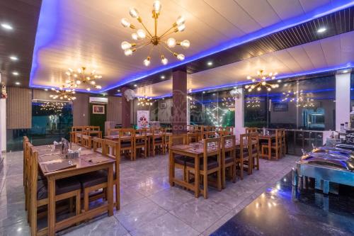 a restaurant with wooden tables and chairs and a chandelier at Seven Corbett in Rāmnagar