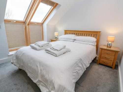 a bedroom with a large white bed with towels on it at 19 Bay Retreat Villas in St Merryn