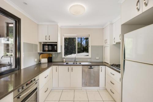 a kitchen with white cabinets and a sink at Perfect CDB & Parkland Fringe! in Toowoomba