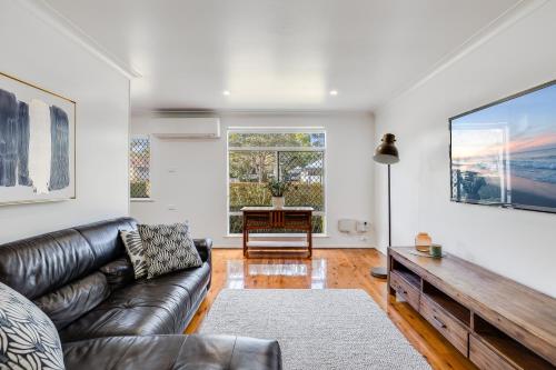 a living room with a leather couch and a table at Eastside Haven - Central & Convenient! in Toowoomba