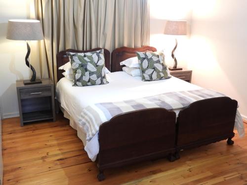a bedroom with a large bed with two lamps at The Ranch House at African Safari Lodge in Grahamstown