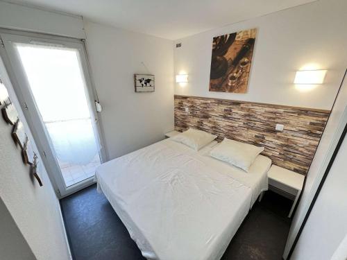- une petite chambre avec un lit blanc et un mur en briques dans l'établissement Appartement 4 pièces avec parking, piscine et proche plage au Cap d'Agde - FR-1-702-19, au Cap d'Agde