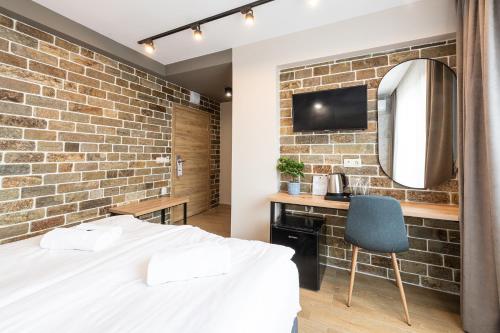a bedroom with a brick wall and a bed and a desk at Хотел Камъните in Burgas