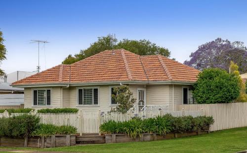 a house with an orange roof with a fence at Cute & Cuddly - Somerset Cottage in Toowoomba