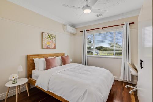a white bedroom with a bed and a window at Cute & Cuddly - Somerset Cottage in Toowoomba