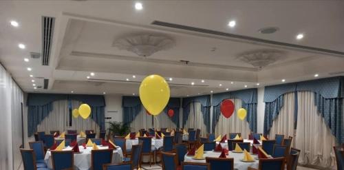 HOTEL CONCORDE في SantʼEgidio alla Vibrata: قاعة احتفالات بالطاولات والبالونات الصفراء على السقف