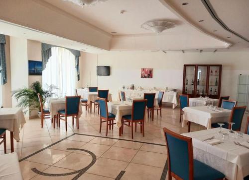 una sala da pranzo con tavoli e sedie bianchi di HOTEL CONCORDE a SantʼEgidio alla Vibrata
