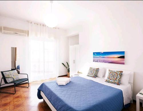 ein weißes Schlafzimmer mit einem blauen Bett und einem Stuhl in der Unterkunft Limonce' Home Vicini a San Vito lo Capo e Palermo CasaVacanze con ampia veranda e Vista a 3 minuti dal mare Alcamo marina in Castellammare del Golfo